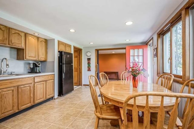 kitchen with tasteful backsplash, black fridge, sink, and light tile patterned floors