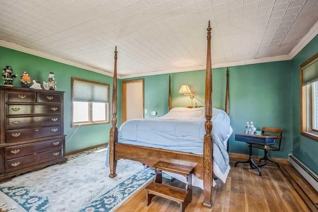 bedroom with crown molding, wood-type flooring, and a baseboard heating unit