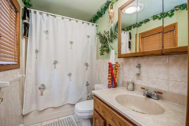 full bathroom with vanity, shower / bath combo with shower curtain, tile walls, tile patterned flooring, and toilet