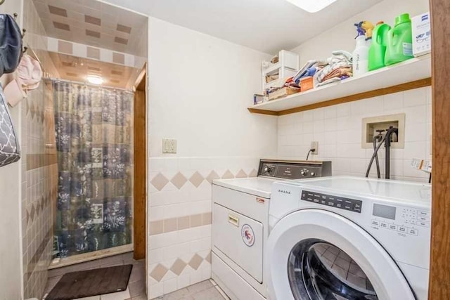 laundry area featuring washer and dryer, light tile patterned floors, and tile walls