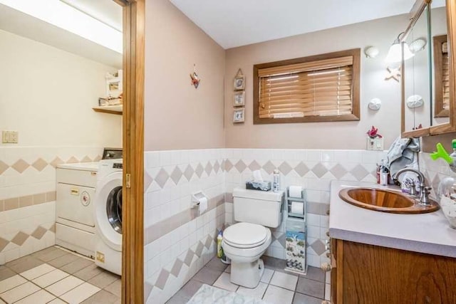 bathroom featuring tile patterned floors, vanity, tile walls, washer / clothes dryer, and toilet