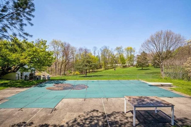 view of swimming pool with a lawn and a diving board