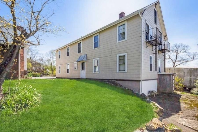 back of house with a yard and a balcony