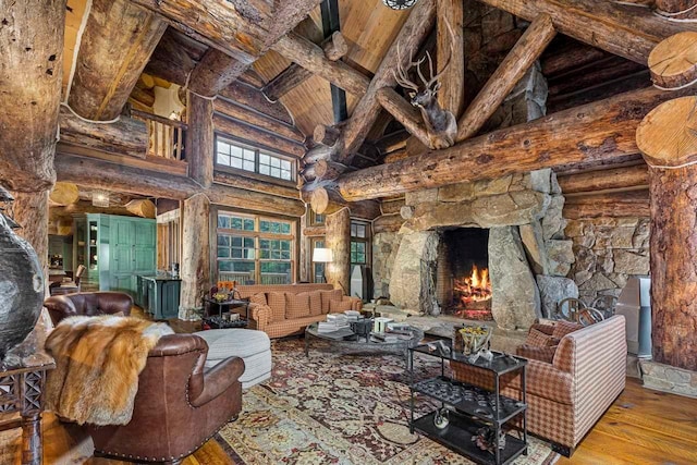 living room with wood-type flooring, high vaulted ceiling, a stone fireplace, and beam ceiling