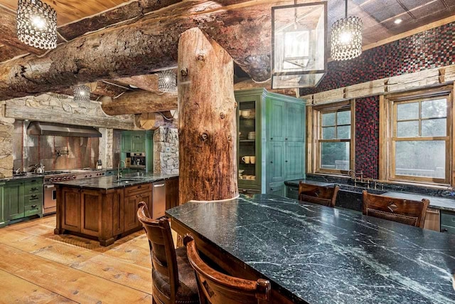 kitchen with sink, high end stainless steel range, green cabinetry, decorative light fixtures, and light hardwood / wood-style floors