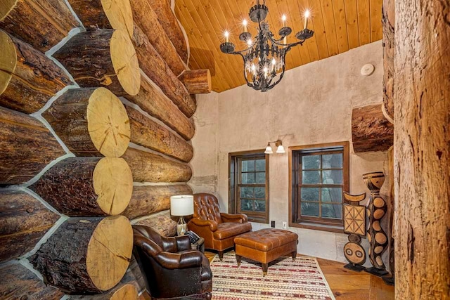 living area featuring wood-type flooring, a towering ceiling, an inviting chandelier, and wood ceiling