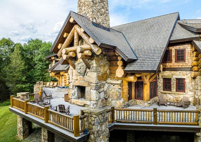 rear view of house featuring a stone fireplace