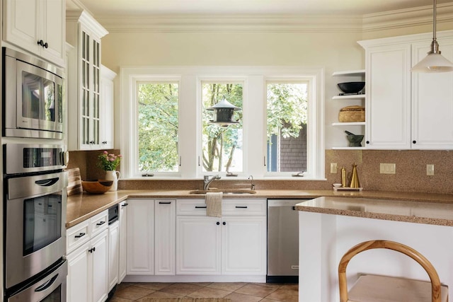 kitchen featuring white cabinetry, sink, tasteful backsplash, pendant lighting, and appliances with stainless steel finishes