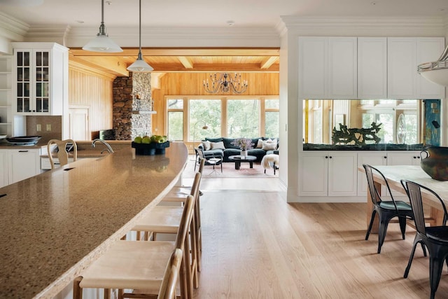 kitchen featuring white cabinets, hanging light fixtures, dark stone countertops, light wood-type flooring, and a notable chandelier