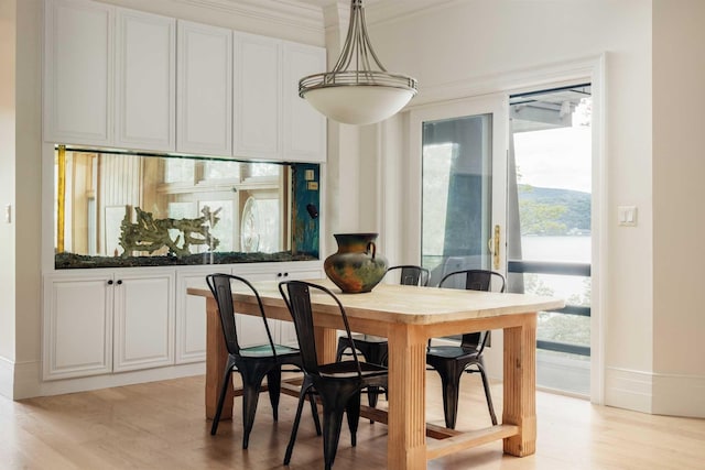 dining area with light wood-type flooring and ornamental molding