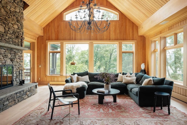 living room featuring wooden walls, high vaulted ceiling, and a stone fireplace