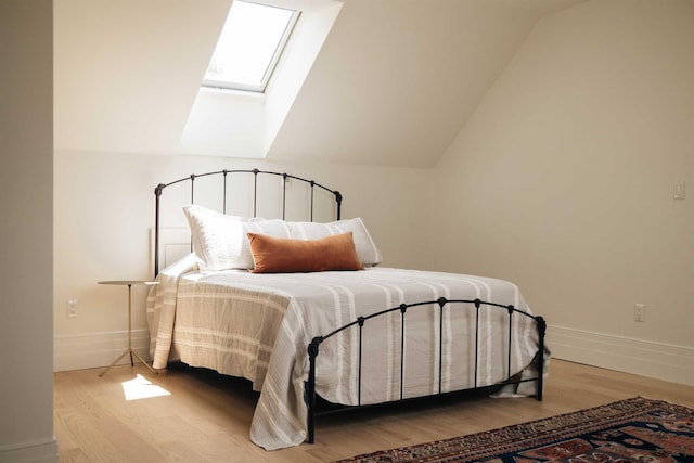 bedroom featuring hardwood / wood-style flooring and vaulted ceiling with skylight