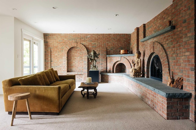 living room featuring carpet floors, a brick fireplace, and brick wall