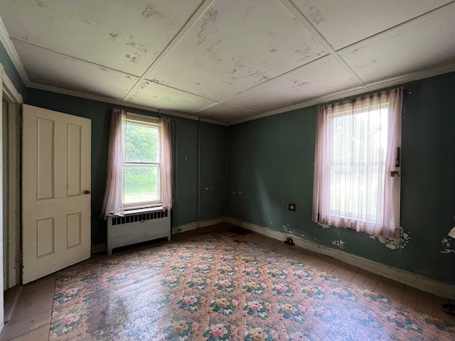 unfurnished room with hardwood / wood-style flooring, crown molding, and radiator