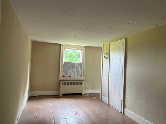 unfurnished room with light hardwood / wood-style floors and radiator heating unit