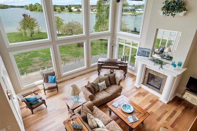 living room featuring a premium fireplace, light wood-type flooring, and a towering ceiling