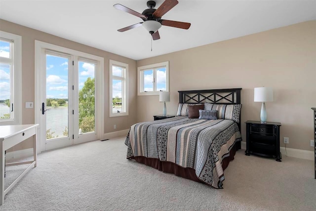 carpeted bedroom featuring access to exterior, multiple windows, and ceiling fan