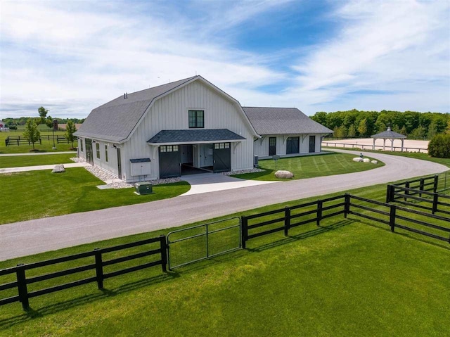 view of front of house with driveway, a gambrel roof, a front lawn, and a fenced front yard