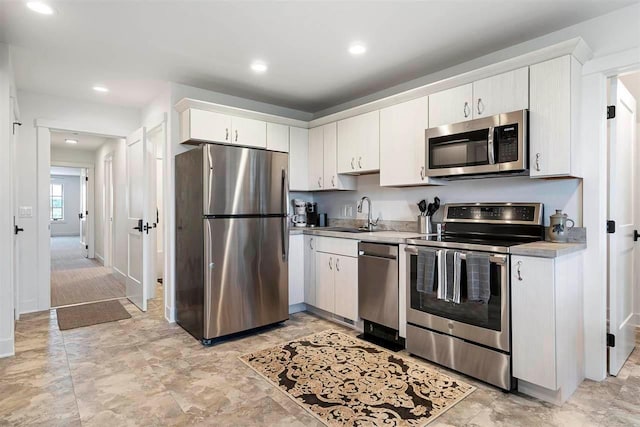 kitchen with recessed lighting, light countertops, white cabinetry, appliances with stainless steel finishes, and a sink