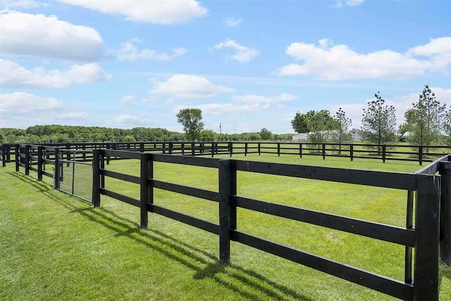 view of gate with a rural view and a lawn