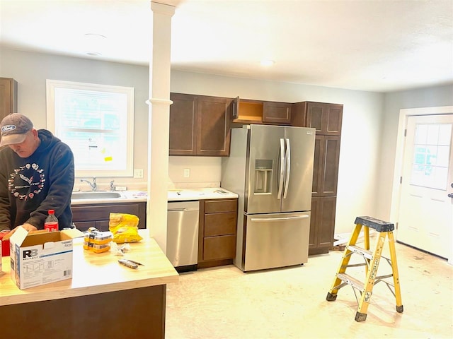 kitchen featuring appliances with stainless steel finishes, dark brown cabinetry, ornate columns, and sink