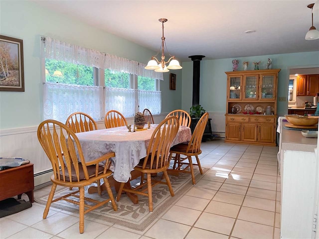 dining space featuring light tile flooring, a chandelier, and a wood stove