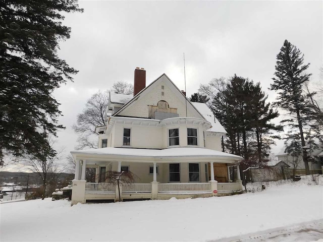 snow covered rear of property with covered porch