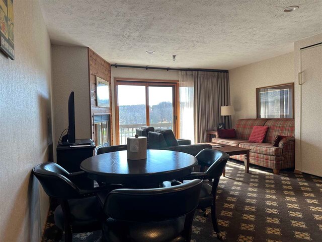 carpeted dining area with a textured ceiling