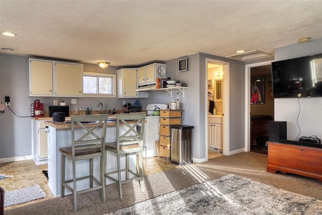 kitchen with white cabinetry, light colored carpet, a kitchen bar, and white stove