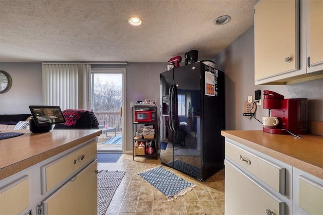 kitchen featuring white cabinets, black fridge, and a textured ceiling