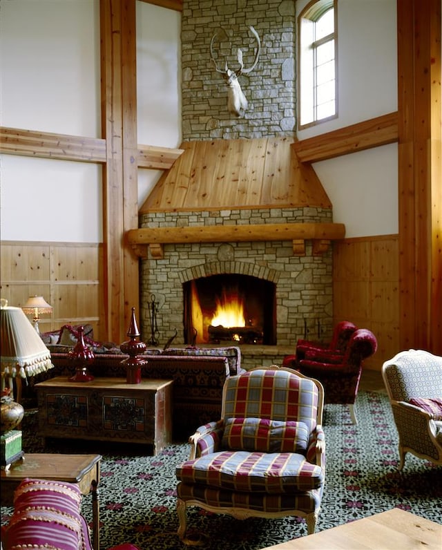 sitting room with wood walls, a large fireplace, and a high ceiling