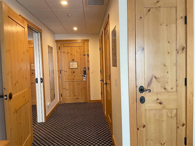 hallway with a paneled ceiling and carpet