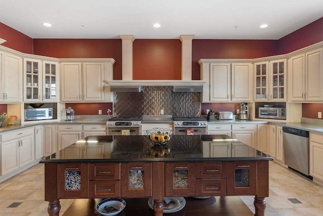 kitchen with premium range hood, dark stone countertops, a center island, and appliances with stainless steel finishes