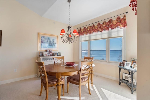 dining area with a water view, light colored carpet, and an inviting chandelier