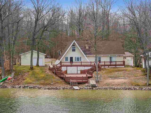 back of house with a storage unit and a deck with water view