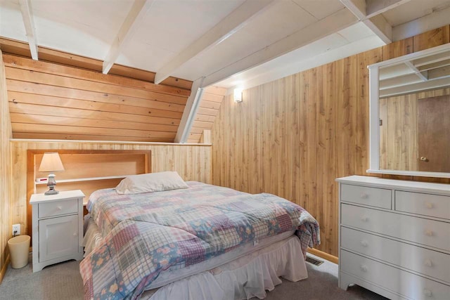 carpeted bedroom featuring beam ceiling and wood walls