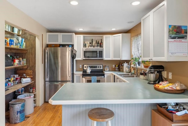 kitchen with kitchen peninsula, appliances with stainless steel finishes, white cabinets, and a kitchen bar