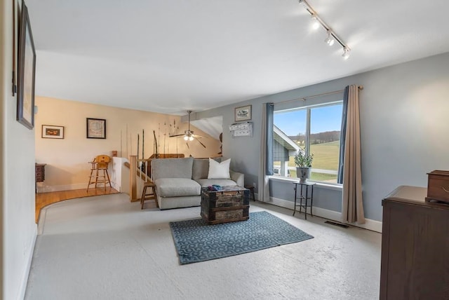 living room featuring rail lighting, ceiling fan, and concrete flooring