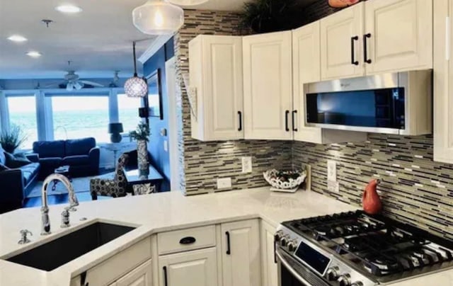 kitchen featuring white cabinetry, stainless steel appliances, sink, tasteful backsplash, and ceiling fan