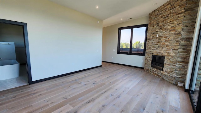 unfurnished living room featuring a fireplace, lofted ceiling, and light hardwood / wood-style floors