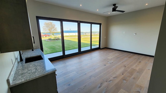 unfurnished room with a water view, light wood-type flooring, and ceiling fan