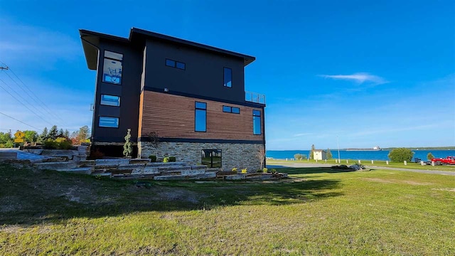 back of house with a yard and a water view