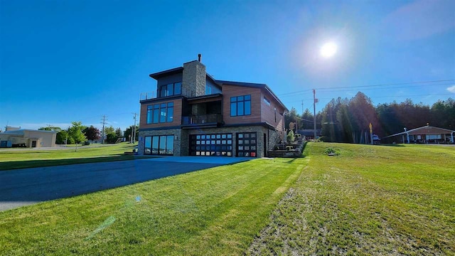 view of front facade featuring a garage, a balcony, and a front lawn