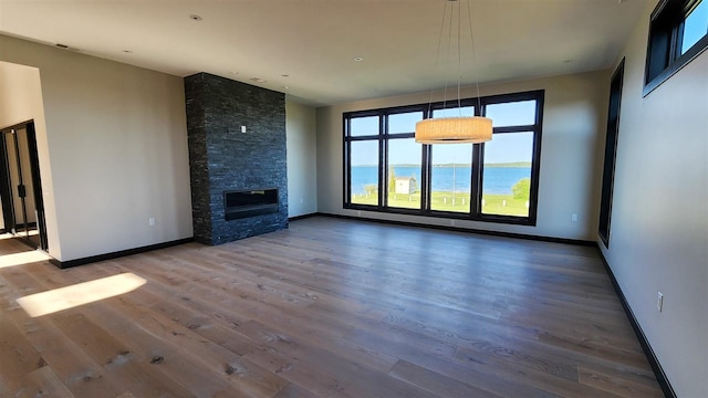 unfurnished living room with a fireplace, wood-type flooring, and a water view