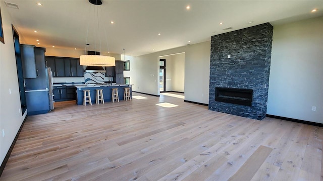 unfurnished living room featuring a stone fireplace and light wood-type flooring