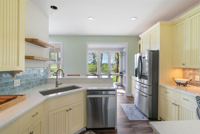 kitchen featuring dark hardwood / wood-style flooring, stainless steel appliances, cream cabinets, sink, and tasteful backsplash