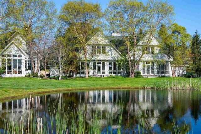 back of property featuring a water view and a lawn