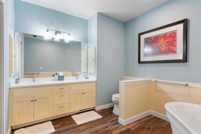 bathroom with a tub, hardwood / wood-style floors, toilet, and dual bowl vanity