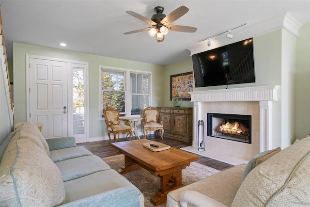 living room featuring a fireplace, track lighting, ceiling fan, and dark hardwood / wood-style flooring