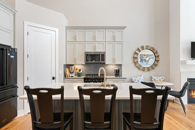 kitchen with decorative backsplash, appliances with stainless steel finishes, sink, and light hardwood / wood-style flooring